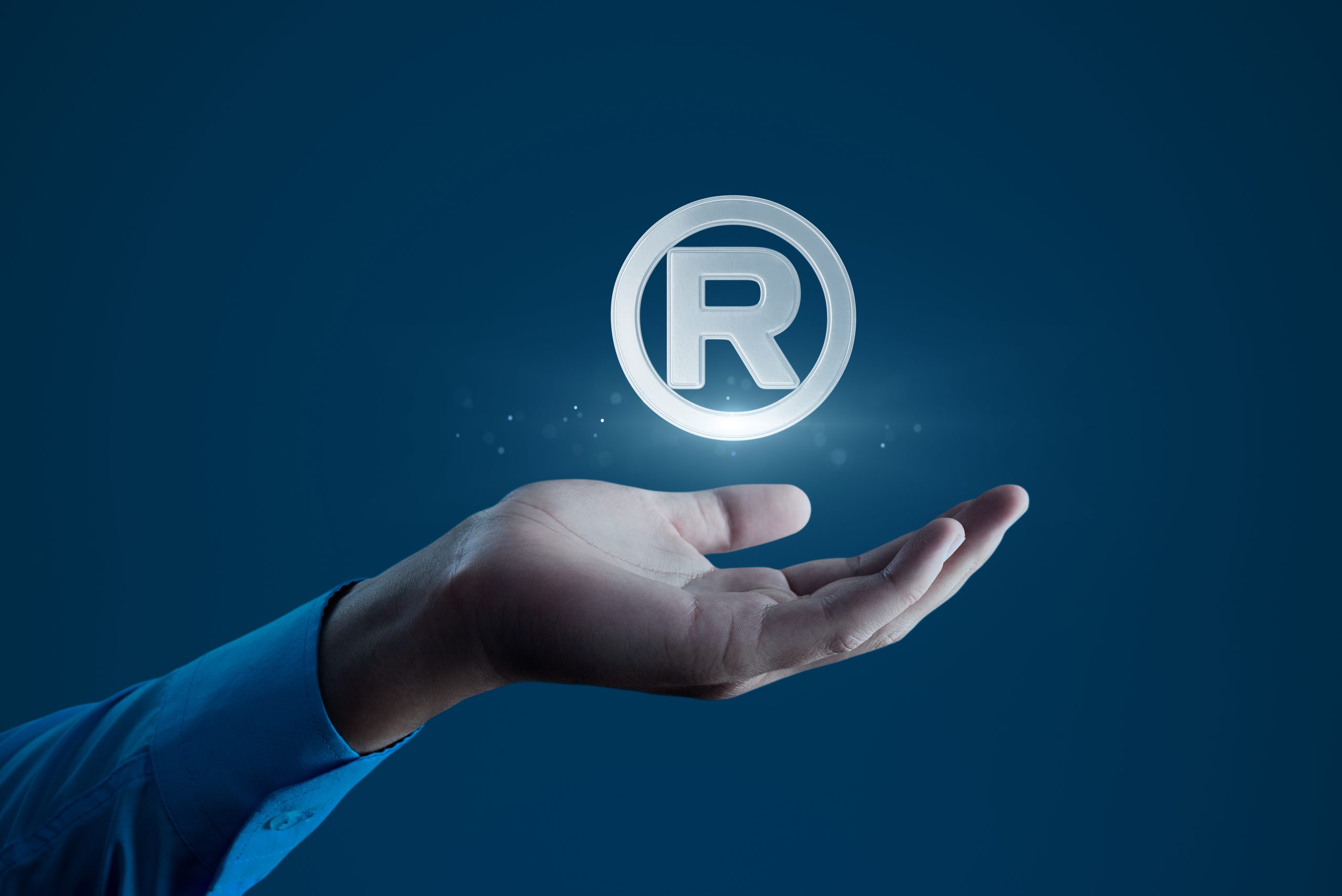 Human Hand Holding R Registered Trademark Symbol for Branding and Legal Concepts.